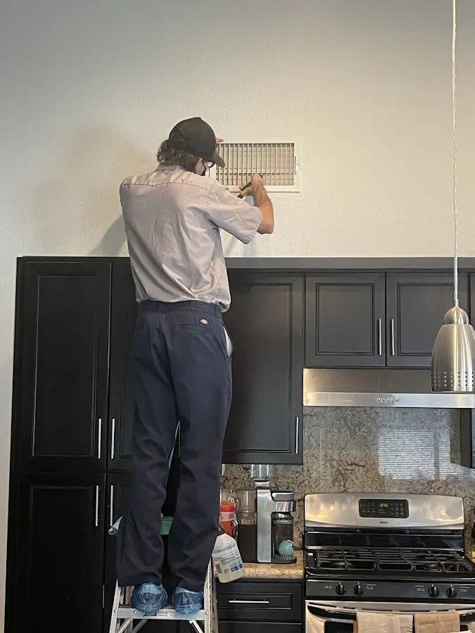 Technician inspecting an air vent during HVAC service in New Brighton